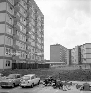 Schanzenbarg: vorn unbefestigtes Gelände, Straße und Parkplatz mit parkenden Pkws und Motorrädern: links dahinter mehrgeschossiges Hochhaus: rechts dahinter unbefestigtes Gelände: hinten rechts zwei viergeschossige Wohnblocks: 20. Juni 1968