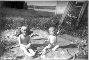 Photographien von Lappland. Zwei nackte Kleinkinder auf einer Decke im Freien