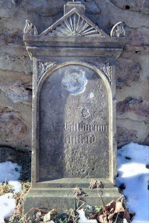 Grabstein vor der Kirchmauer auf dem alten Friedhof