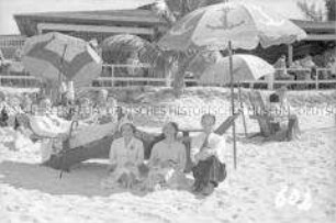 Touristen in Straßenbekleidung am Strand