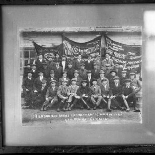 Gruppenfoto mit Plakaten mit kyrrilischer Aufschrift, aufgenommen wohl in der Sowjetunion