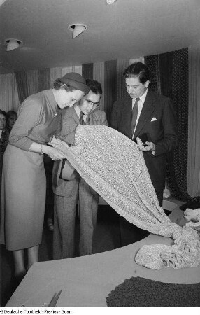 Drei Personen begutachten eine Textilie der Leipziger Herbstmesse 1954