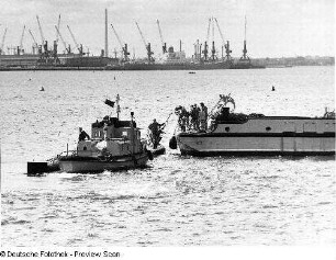 Deutschland . Nationale Volksarmee - Seestreitkräfte. Übergabe von Dienstmaterial zwischen einer Motorbarkasse und einem Kampfschiff in einem Hafen