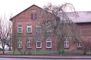 Hauptstraße 24: Bauernhaus aus Backstein, mit umlaufendem Gesims: links giebelständiges Wohnhaus, Straßenfront: rechts traufständiger Wirtschaftstrakt [angeschnitten]