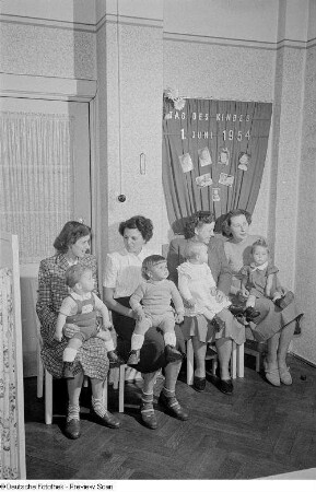 Vier Mütter mit Kleinkindern auf dem Schoß