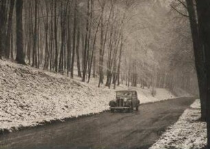 Winter. Ein Personenkraftwagen (DKW) fährt auf einer Straße in einem verschneiten Wald