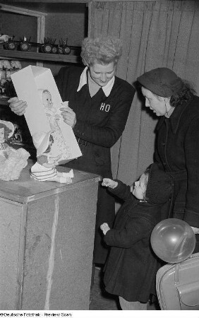 Handelsorganisation-Kaufhaus präsentiert einer Frau und einem Kind eine Puppe
