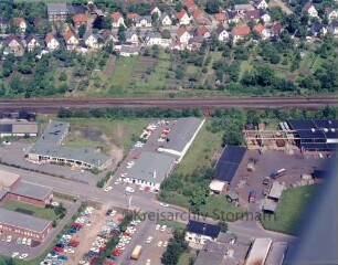 Hermann & Rindelaub KG (Bogenstraße 42): Luftbild des Betriebsgeländes: im Vordergrund Bogenstraße und Befestigungstechnik Ahrensburg (BEA), in der Bildmitte Bahnstrecke Hamburg-Lübeck, links Günther Brinckmann Baustoffe, rechts Wilhelm Rohde KG und Rohrbogenwerk Böhling, im Hintergrund Wohngebiet an der Hamburger Straße