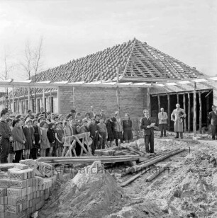 Volksschule Tannenweg: zweiter Erweiterungsbau mit zwei Pavillons: Richtfest: Ansprache von Bürgermeister Herbert Rübner: links und dahinter Schüler, Lehrer und Gäste: hinten eingedeckter Pavillon: vorn Sandhaufen und Baumaterial