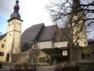 Ansicht von Südosten mit Kirche (Kirchturm 1716 - Langhaus 1969) sowie frühgotischem Torturm mit anschließender Kirchhofmauer (Wehrgang im 18 Jh abgetragen)