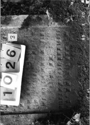 Grabstein 1026 (Index: 99751285) Material: Sandstein Zustand: stark verwittert Maße HxBxT: 120x66x8 cm Beschreibung: Stele, geschwungener Abschluß, Schriftfeld eingetieft Symbolik: Medaillon: Grabstein 1026B