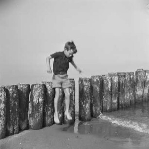 Kind der Gremmlers springt von einem Wellenbrecher am Strand von Henkenhagen (heute: Ustronie Morskie)