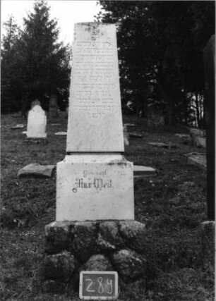 Grabstein 289 (Index: 100090180) Material: weißer Marmor, unterer Sockel-Kalkstein Zustand: gut Maße HxBxT: 200x40x33 cm Beschreibung: Obelisk, Doppelsockel, unterer Sockel rustica: Grabstein 289