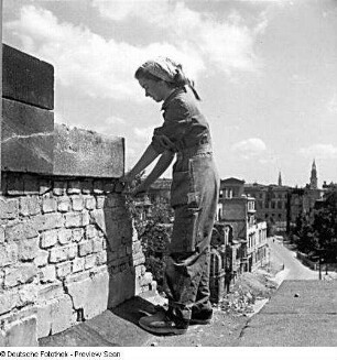 Junge Frau bei der Arbeit an einer höhergelegenen Ziegelwand