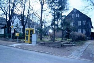 Straße, daneben Grünanlage; Telefonzelle und Briefkasten
