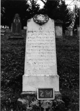 Grabstein 281 (Index: 100090164) Material: weißer Marmor, unterer Sockelteil Kalkst. Zustand: gut Maße HxBxT: 144x47x13 cm Beschreibung: Stele, getreppt. Sockel, unterster Sockelteil rustica, giebelartiger Abschluß Symbolik: Kranz um Abschluß Steinmetz: A. Weber Diessenhofen: Grabstein 281