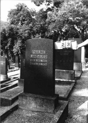 Grabstein 23 (Index: 99793185) Material: schwarzer Granit Zustand: gut Maße HxBxT: 122x47x14 cm Beschreibung: Stele mit Segmentbogenabschluß, Schriftzeilen eingetieft, getreppter Sockel, Grabeinfassung: Grabstein 23