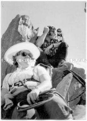 Drei Menschen, angeseilt, auf Felsgestein sitzend