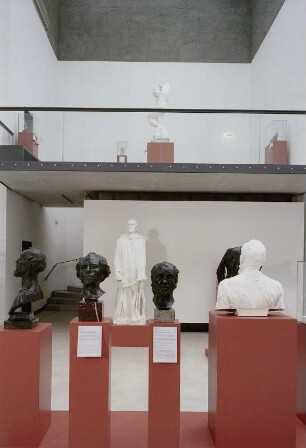 Raumaufnahme Ausstellungssaal. Blick über die Gruppe von Büsten und Porträtköpfen zur Empore