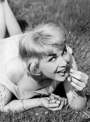 Lüneburger Heide. Das Model Hannelore liegt im Gras. Sie lässt sich Kirschen schmecken