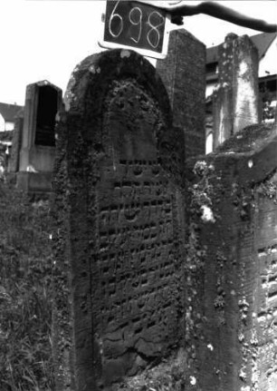 Grabstein 698 (Index: 100104852) Material: Sandstein Zustand: teilweise stark verwittert, abgeblättert, teilweiser Textverlust Maße HxBxT: 132x60x10 cm Beschreibung: Stele, eingezogener Rundbogenabschluss, Schriftfeld eingetieft: Grabstein 698