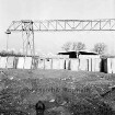 Gewerbegebiet: Aufbau einer Fabrikhalle: Lagerung von Beton-Fertigteilen: Laufkran mit Laufkatze: dahinter Hallengerüst: im Vordergrund Schatten des Fotografen