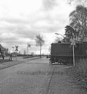 Industriegleis der Bahnstrecke zwischen Glinde und Hamburg-Tiefstack [ehemalige Südstormarnsche Kreisbahn]: Bahnübergang mit Andreaskreuz: rechts dahinter Diesellok (V 3): hinten links Tankstelle