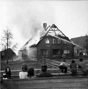 Brand: Reetdachhaus auf Nachbarhof Holm: Funkenflug vom Brand des Hofes von Walter Ellerbrock: brennendes Dach: links Feuerwehrmänner beim Löschen: im Vordergrund Zuschauer