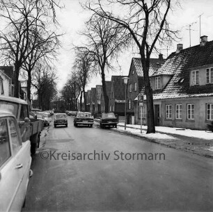 Pölitzer Weg: rechts und links Wohnhäuser: davor Bäume: vorn und hinten links Kleinlaster und Pkws: Winter