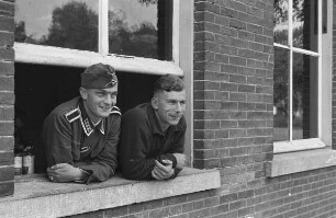 Zweiter Weltkrieg. Niederlande unter deutscher Besatzung. Porträt zweier Wehrmachtsangehöriger, aus einem Fenster schauend (wohl bei Den Haag)