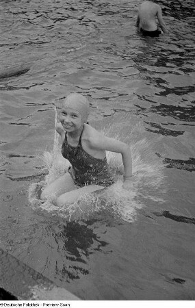 Mädchen beim Sprung ins Schwimmbecken eines Freibades