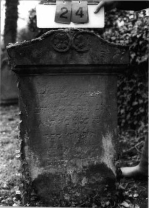 Grabstein 24 (Index: 100100061) Zustand: stark verwittert Maße HxBxT: 110x55x15 cm Symbolik: Blüte: Grabstein 24