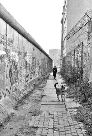 Frau mit Hund an der Mauer