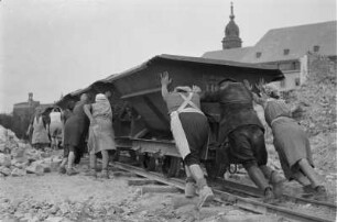 Enttrümmerung im Stadtkern : Dresden-Altstadt. Trümmerbahn, von Frauen und einem Mann geschoben; im Hintergrund Rathaus und Turm der Kreuzkirche