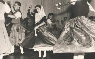 Folklore. Tänzer führen einen Volkstanz auf. Im Hintergrund die dazugehörige Musikgruppe