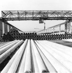 Coswig. VEB (B) Beton- und Kieswerk Coswig. Lagerplatz mit gestapelten Rohren. Blick gegen Brückenkran (mit Rohr)