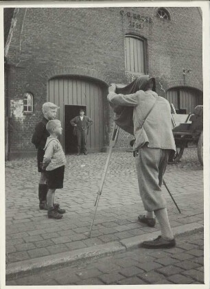 Fotograf wird beim Fotografieren mit einer Plattenkamera auf einem Bauernhof von Kindern bestaunt