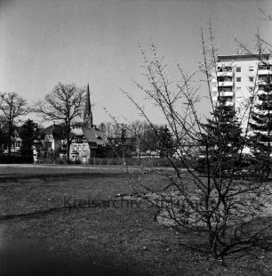 Kurpark: vorn Grünfläche: dahinter Kurparkallee mit Stadtvillen und Paar: rechts Hochhaus "Liebe": hinten links Peter-Paul-Kirche