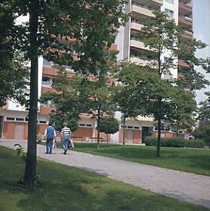 Hansjakob, Gottfried; München - Neuperlach Mitte; Wohnring Neuperlach - Grünanlage mit Möblierung vor Wohnanlage, Aufnahme mit Passanten