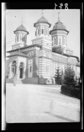 Kirche in romanischem Stil mit drei Türmen und gestreiftem Mauerwerk