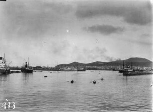 Hafen : Ruderboote fahren durch den Hafen, im Hintergrund die Stadt