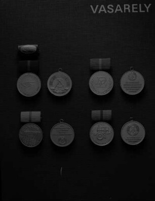 Vier Medaillen der Deutschen Demokratischen Republik (DDR). Oben: Medaille für hervorragende Leistungen im Verkehrswesen der DDR (vergoldet; 30 mm Durchmesser; 1975 gestiftet) an Spange (blau bezogen; 12,5 x 25 mm) inklusive Interimsspange mit vergoldeter Miniatur der Medaillenvorderseite und Medaille für hervorragende Leistungen im Bereich der haus- und kommunalwirtschaftlichen Dienstleistungen der DDR (vergoldet; 30 mm Durchmesser, 1975 gestiftet) an Spange (blau bezogen; 13 x 25 mm). Jeweils Avers und Revers (ohne Spange). Unten: Medaille für hervorragende Leistungen in der Wasserwirtschaft der DDR (vergoldet; 30 mm Durchmesser; 1975 gestiftet) an Spange (hellblau bezogen; 13 x 25 mm), Avers mit stilisierter Talsperre und Revers (ohne Spange) sowie Medaille für hervorragende Leistungen in der metallverarbeitenden Industrie der DDR (vergoldet; 30 mm Durchmesser; 1975 gestiftet) an Spange (blaugrau bezogen; 12,5 x 25 mm), Avers und Revers