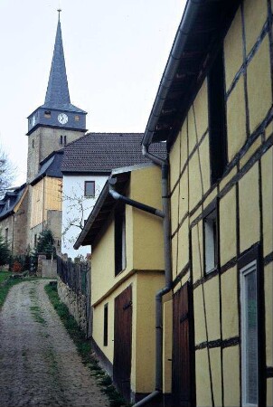 alter Pflasterweg zur Kirche; rechts renoviertes Fachwerkgebäude