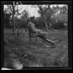 [Mesnil-en-Arrouaise (?) (Dep. Somme, Frankreich)]: Hauptmann Eigl auf einem Stuhl im Freien