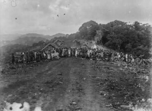 Ankunft der Karawane : Ankunft der Karawane vor einer Siedlung. Die Mitglieder haben sich auf der Straße aufgestellt und schauen in Richtung des Fotografen