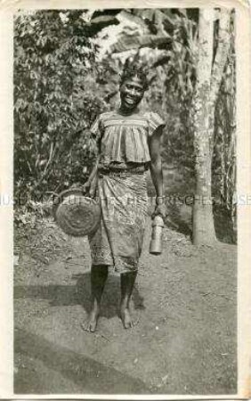 Porträt einer afrikanischen Frau, einen Mörser und einen Stampfer tragend
