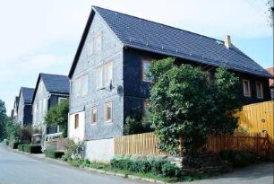 Straße mit Häusern, vorn Vorgarten am Haus