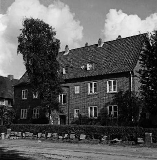 Hebbelstraße: Ausbau: vorn unbefestigte Straße, Stapel mit Gehwegplatten, Mülleimer: dahinter Wohnhäuser der Gemeinnützigen Baugenossenschaft Bad Oldesloe mit Vorgärten
