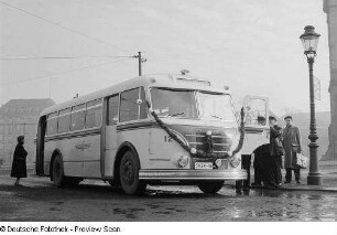 Personen betrachten einen mit Girlanden geschmückten Omnibus H6B