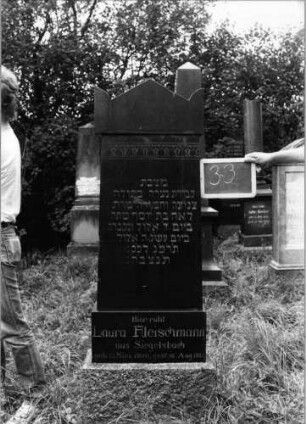 Grabstein 33 (Index: 99753476) Material: Granit Zustand: gut Maße HxBxT: 170x49x18 cm Beschreibung: getreppter Sockel, Stele, Giebel mit Eckakroteren Symbolik: Blütenfries: Grabstein 33